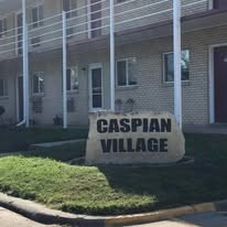 A sign that says Caspian Village in front of a building.