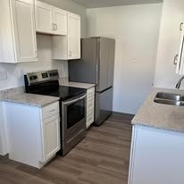 A kitchen with white cabinets and a black stove top oven.