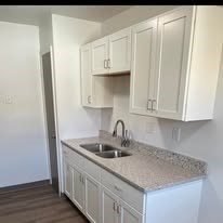 A kitchen with white cabinets and a granite counter top.