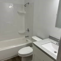 A white toilet sits next to a white sink in a bathroom.