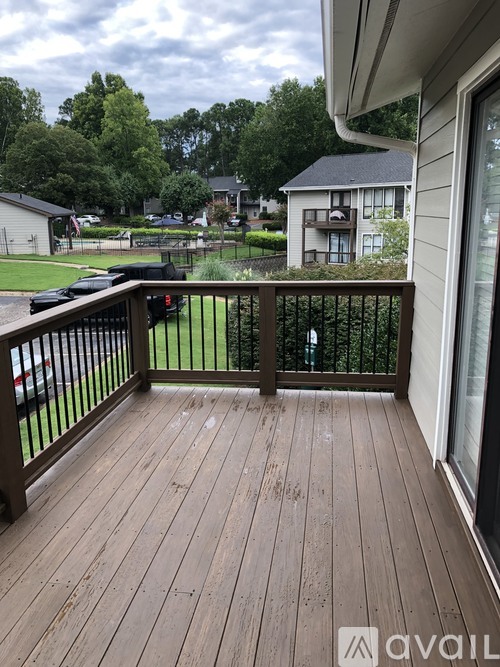 A wooden deck with a railing and a view of a grassy area and trees.