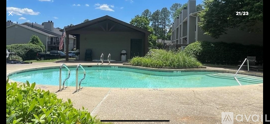 A pool with a diving board and a small building in the background.