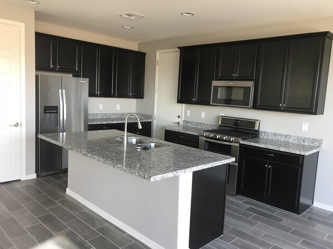 A kitchen with black cabinets and a granite countertop.