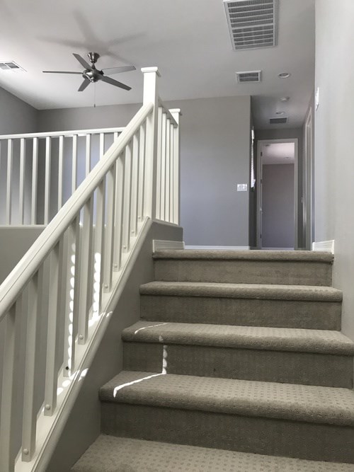 A staircase with a fan in the room.