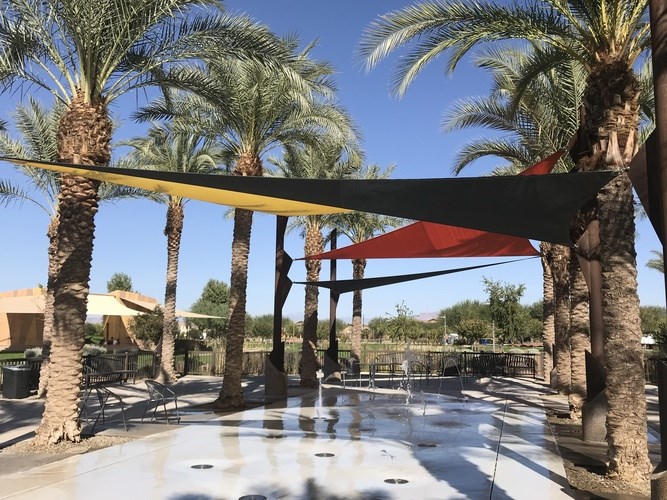 A pool area with palm trees and a red and black striped awning.