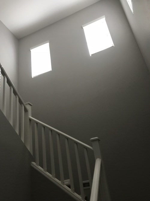 A staircase with a railing and two windows.