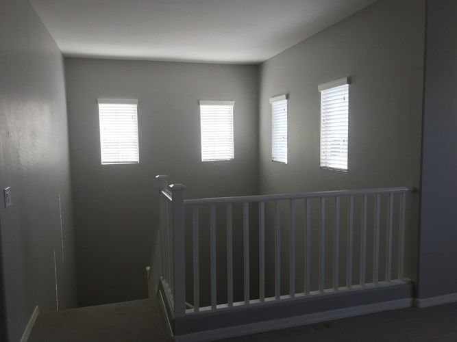 A room with a white railing and three windows.