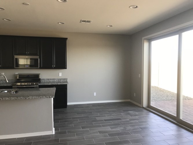 A kitchen with black cabinets and a granite countertop.