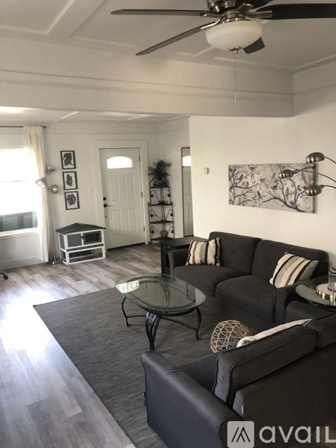 A living room with a black couch and a glass coffee table.