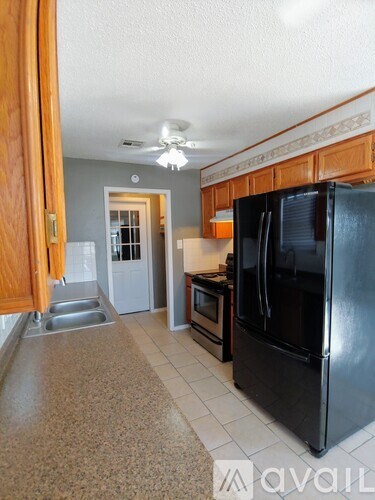 A kitchen with a black refrigerator and wooden cabinets.