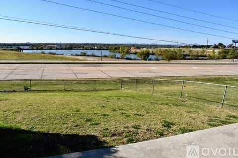A grassy field with a fence and a road in the foreground.