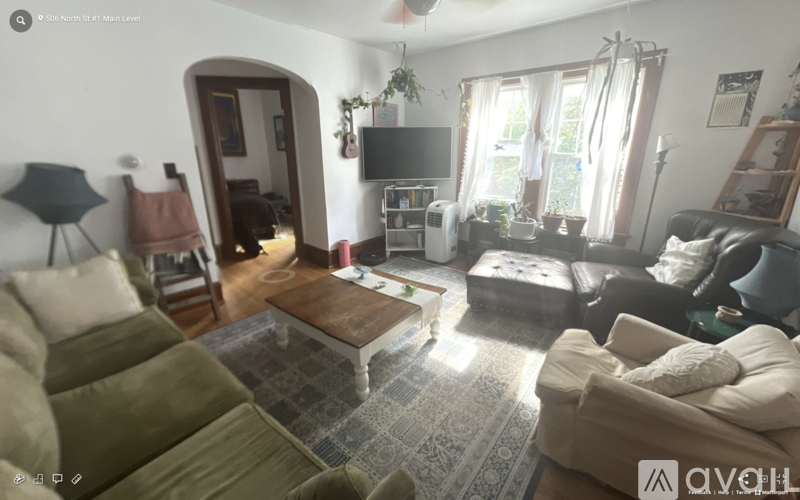 A living room with a couch, a chair, a coffee table, and a television.