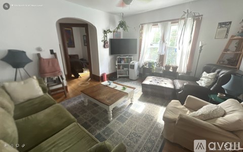 A living room with a couch, a chair, a coffee table, and a television.