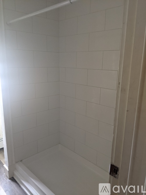 A white tiled bathroom with a white shower stall.