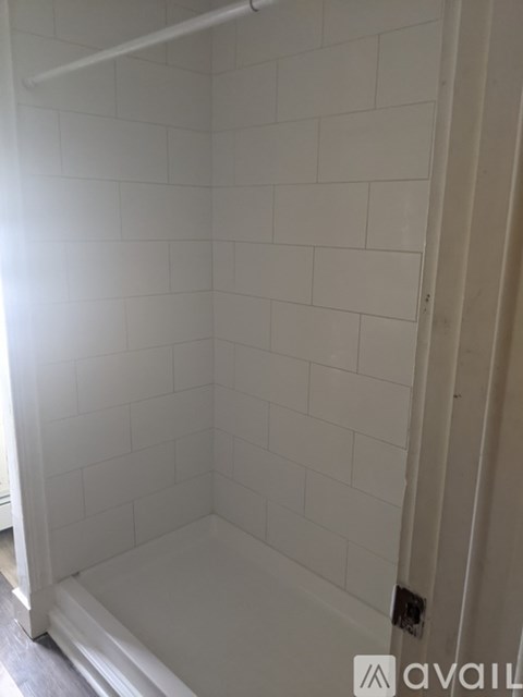 A white tiled bathroom with a white shower stall.