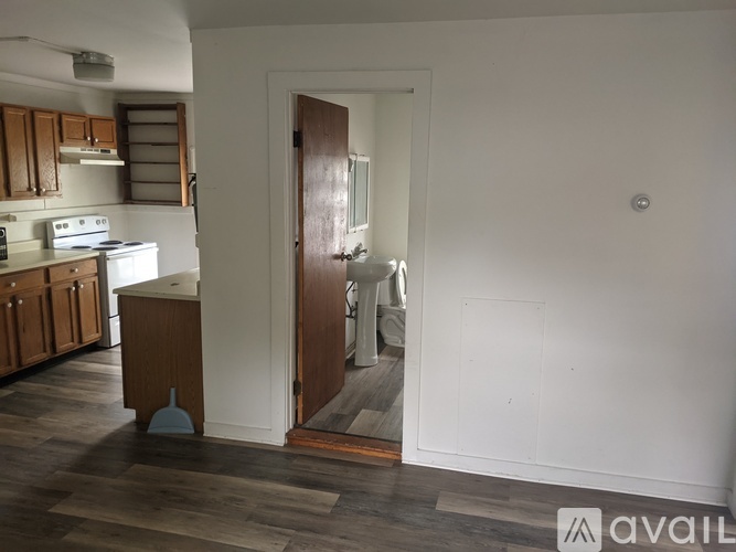 A kitchen with wooden cabinets and a white countertop with a doorway leading to another room.
