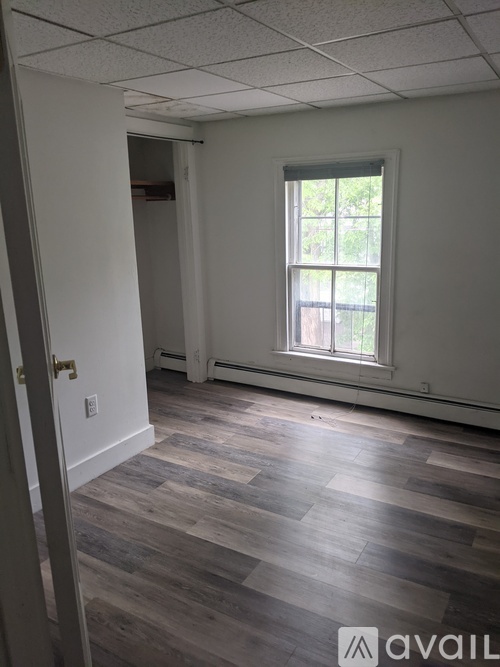 A room with a window and wooden flooring.