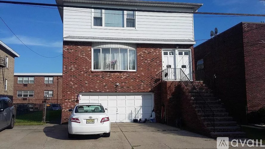 A white car is parked in front of a brick house.