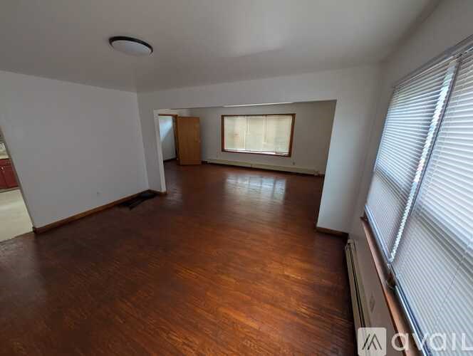 A room with wooden flooring and a window with blinds.