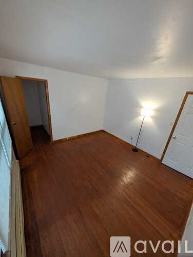 A room with wooden flooring and a window with blinds.