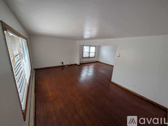 A room with wooden floors and two windows.