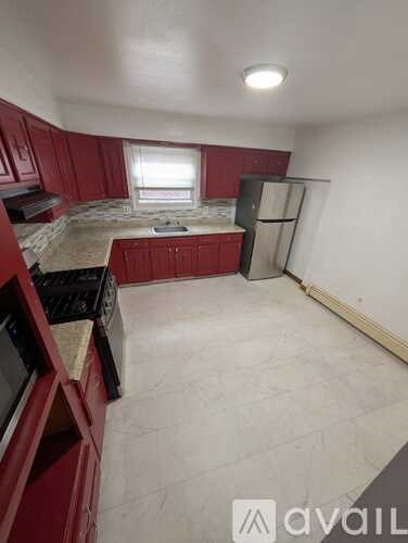 A kitchen with red cabinets and a black stove top oven.