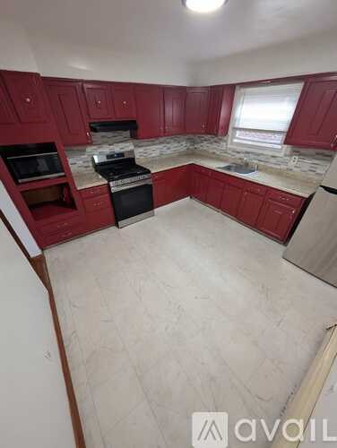 A kitchen with red cabinets and a black stove top oven.