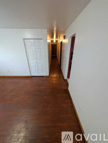 A hallway with a white door and a brown floor.