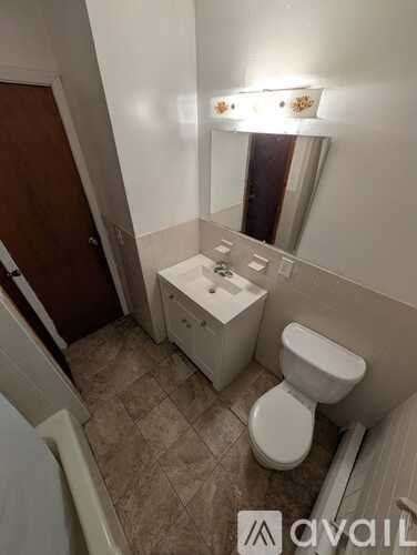 A bathroom with a toilet, sink, and mirror.