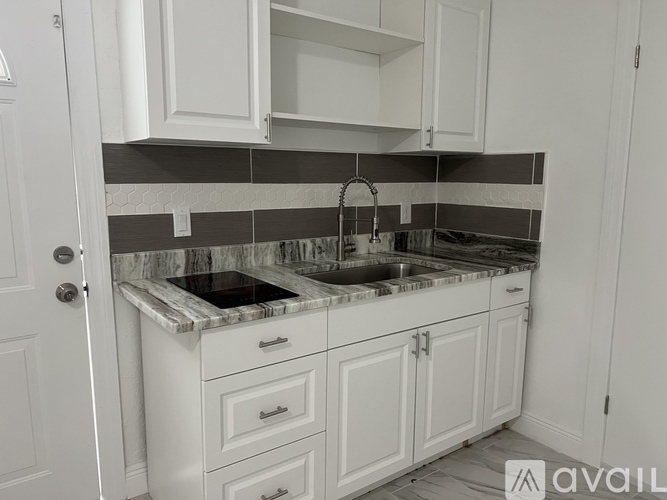 A kitchen with white cabinets and a marble countertop.