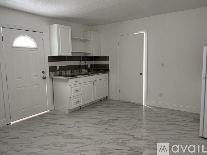 A kitchen with white cabinets and a marble floor.