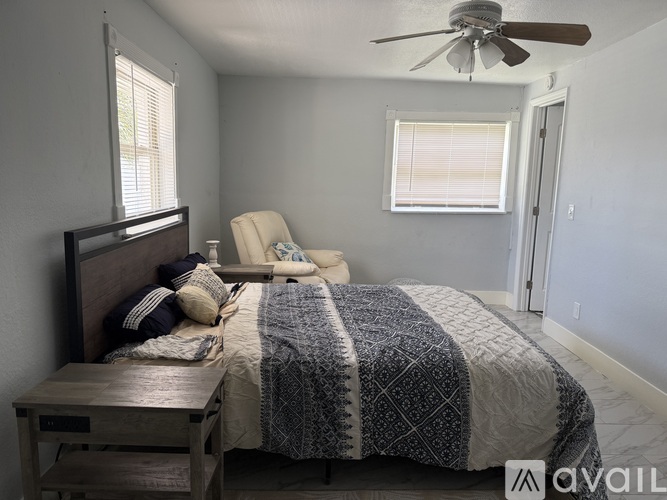 A bedroom with a bed, chair, and ceiling fan.