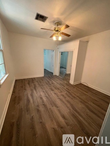 A room with a ceiling fan and wooden flooring.