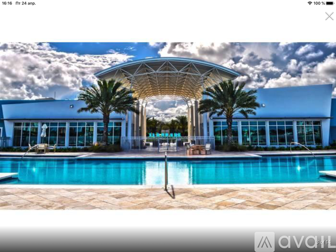 A large building with a pool in front and palm trees around it.