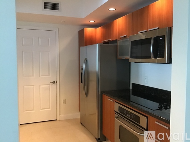 A kitchen with a refrigerator, microwave, oven and a door.