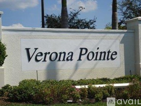 A white sign with black lettering that says "Verona Pointe" in front of some greenery.