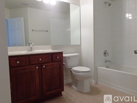 A white toilet sits in a bathroom with a wooden vanity.