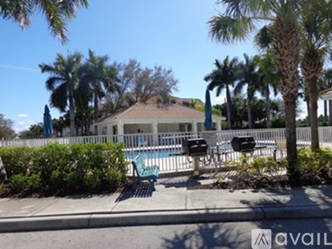 A house with a pool surrounded by a fence and palm trees.