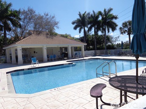 A pool with a table and chairs and a house in the background.