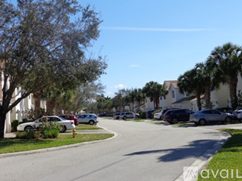 A street with cars parked on the side and trees lining the road.