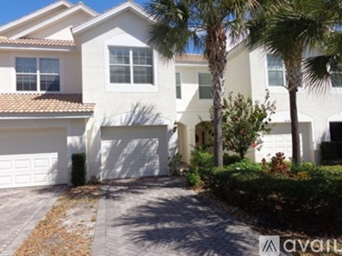 A white house with a brown roof and a garage door.