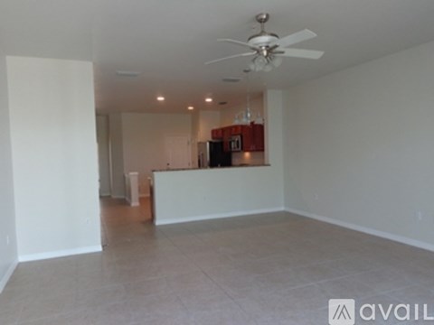 A spacious room with a fan on the ceiling and a bar area in the corner.