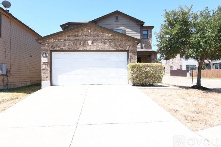 A house with a white garage door and a tree in front.
