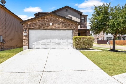 A house with a white garage door and a tree in front.