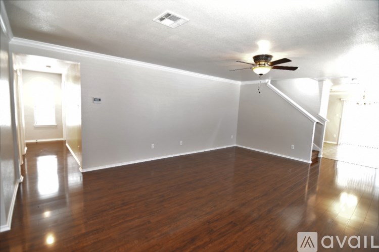A room with a ceiling fan and wooden flooring.