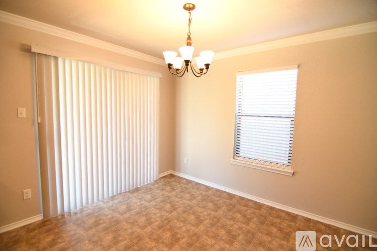 A room with a chandelier, a window with blinds, and a door with a window blind.