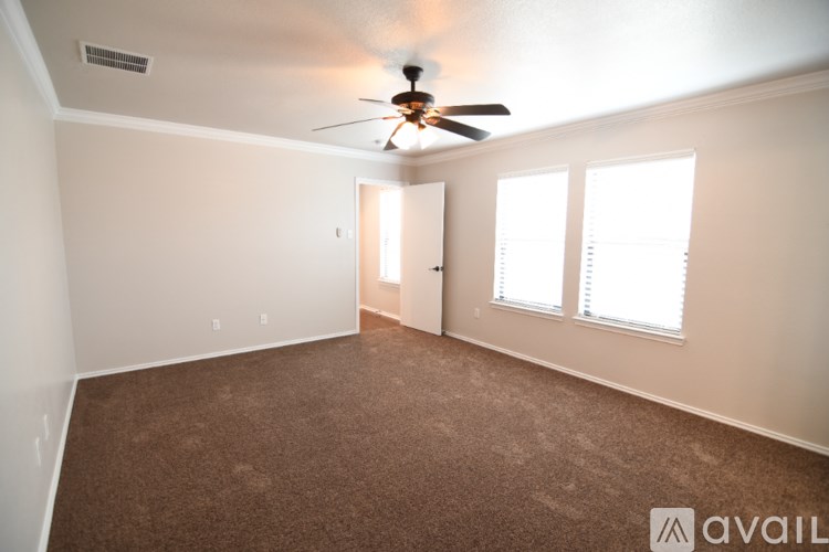 A room with a ceiling fan and carpeted floor.