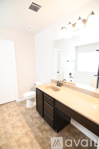 A bathroom with a toilet, sink, and mirror.
