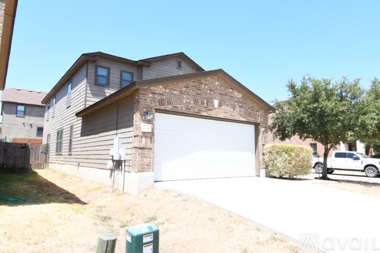 A house with a garage and a tree in front of it.