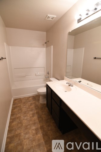 A bathroom with a toilet, sink and mirror.